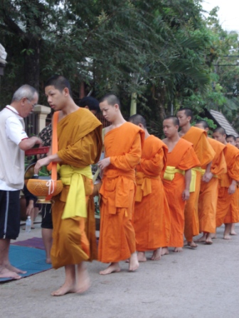 Boeddhistische monniken op bedelronde door de stad. Iedere morgen bij zonsopgang halen ze op die manier hun enige maaltijd bij mekaar.